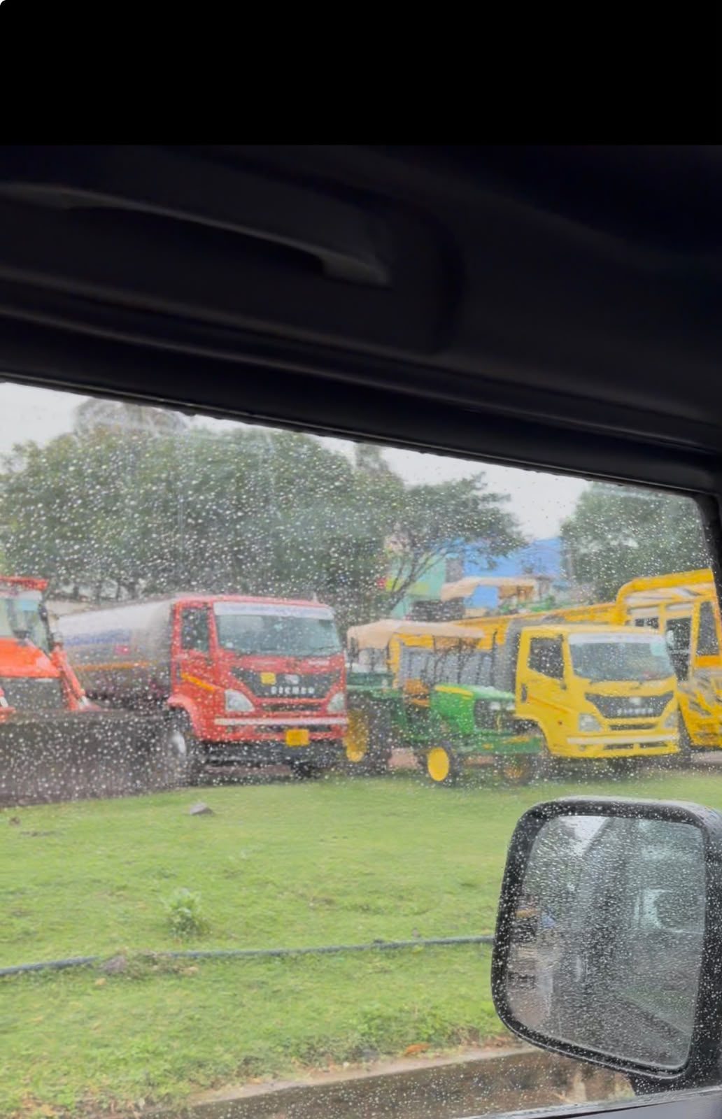 Trucks and equipment of The Royal Mahaveer Roadlines lined up at the yard in the rain